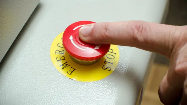 A finger on an emergency stop button