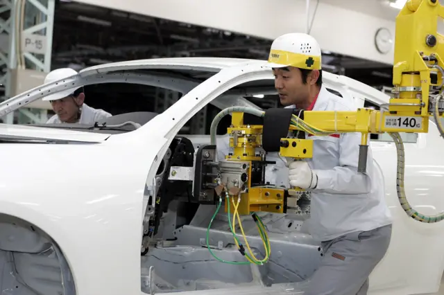 A worker operates machinery on a Nissan production line in Japan