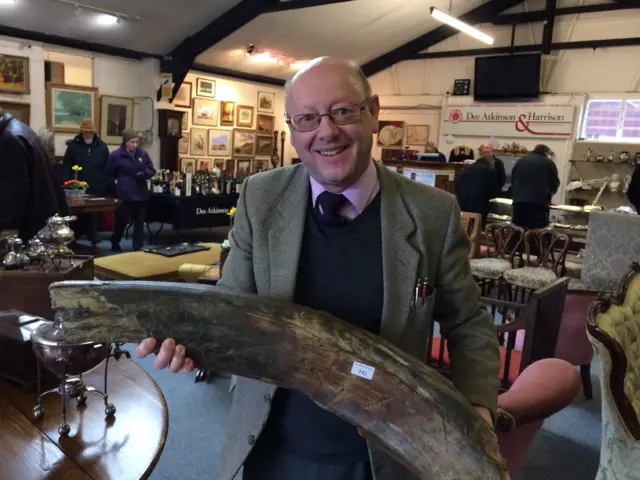 Auctioneer holding a giant tusk