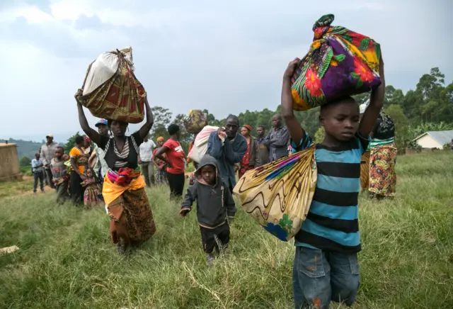 Congolese people carry their belongings after they crossed the border from the Democratic Republic of Congo to be refugees at Nteko village in western Uganda on January 24, 2018