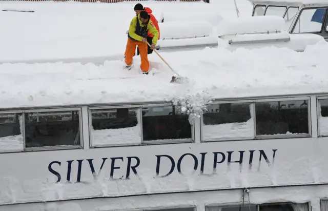 Man clears snow from boat