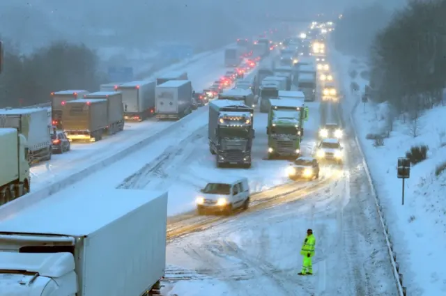 Drivers manoeuvre their cars past stationary lorries on the M80 Haggs