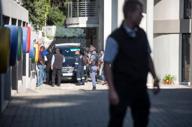 Uniformed and plainclothes police officers are seen inside the compound of the controversial business family Gupta while cars belonging to the Hawks, The Directorate for Priority Crime Investigation, are stationed outside, in Johannesburg, on February 14, 2018.