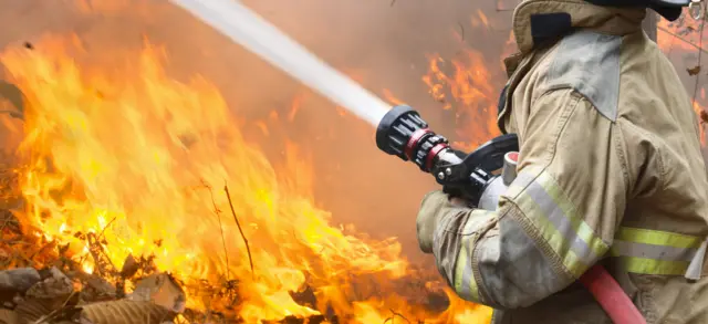 A firefighter using a hose on a fire