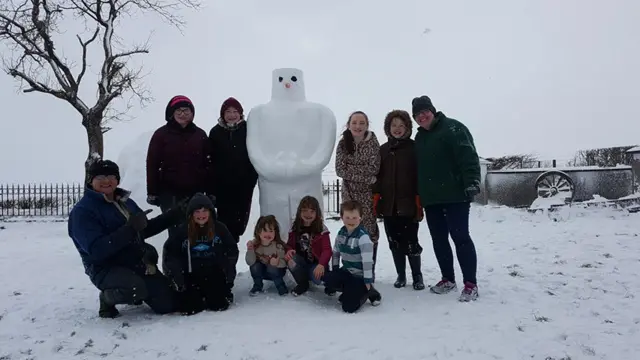 Family and friends work together to make a snowman