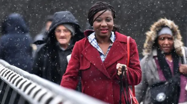 People walking as snow falls