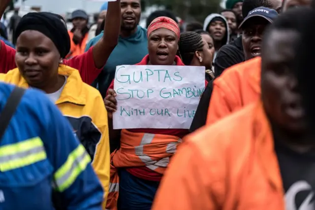 Employees and contractors of the Optimum Coal Mine in Hendrina, owned by the controversial Gupta family, demonstrate with a placard reading "Guptas - stop gambling with our lives" in front of the gates of the mine in Hendrina, South Africa