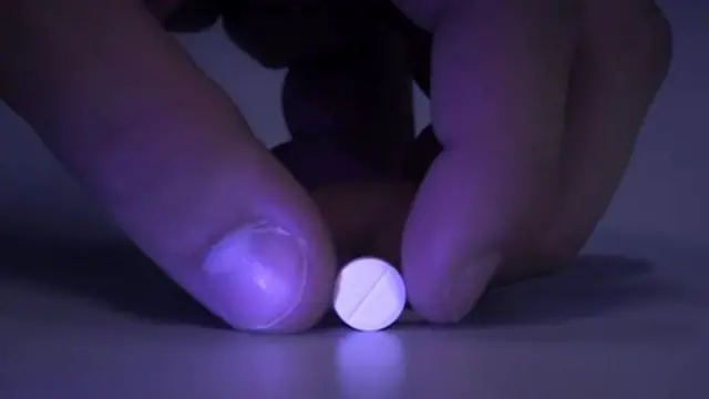 A person holding a white pill