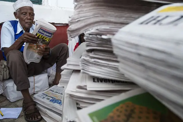 A newspaper vendor sorts the morning papers as they arrive by ferry from the mainland in historical Stone Town, on November 2, 2015