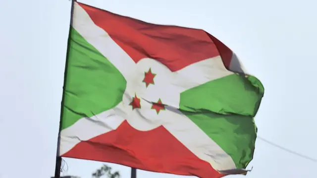 A boy with carries an umbrella near a Burundian flag in Bujumbura on July 20, 2015.