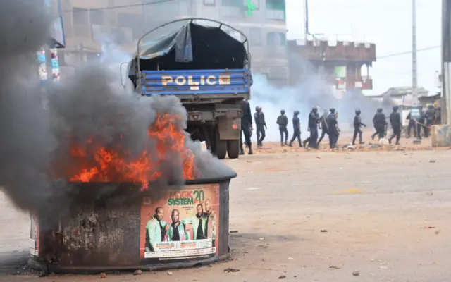 A fire burns as Guinean riot police officers patrol following clashes with protesters in a district of Conakry on November 21, 2017.