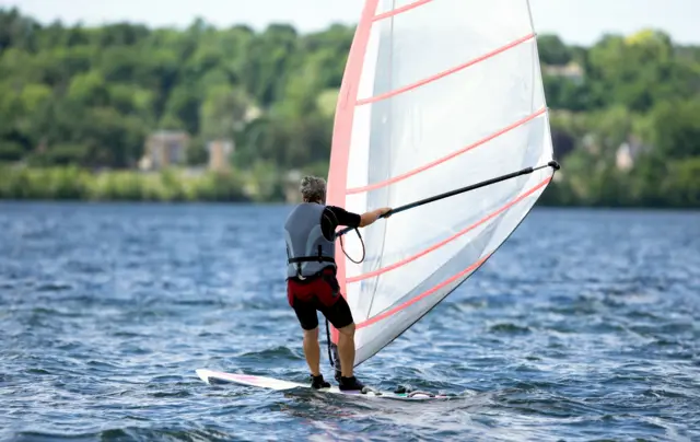 A man windsurfing on a lake