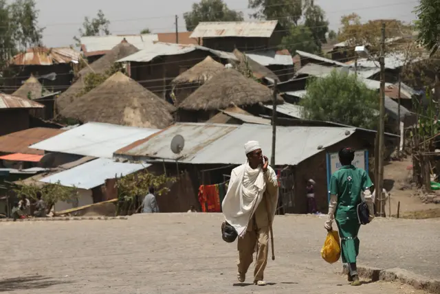 People walk past houses typical for the region near the Lalibela holy sites in Ethiopia.