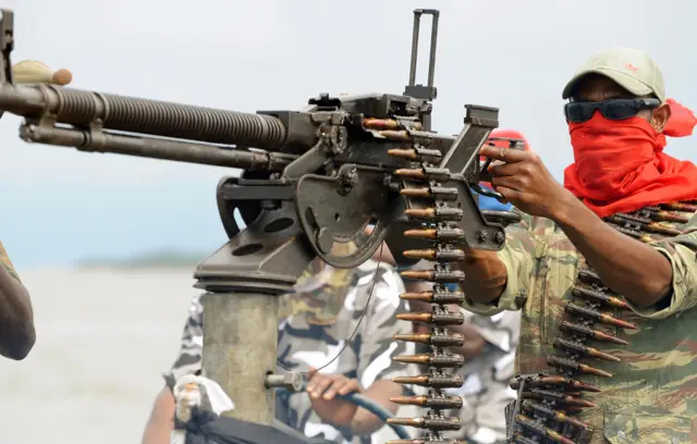 A fighter of the Movement for the Emancipation of the Niger Delta (MEND), poses with a heavy machine-gun at the militia"s creek camp in the Niger Delta on September 17, 2008.