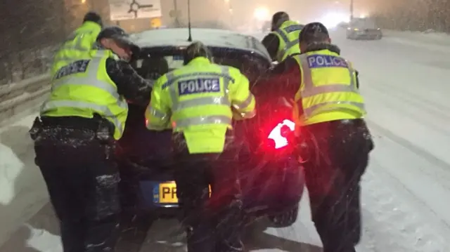 Officers push vehicle stuck in snow