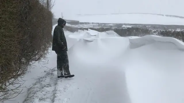 A man walks down a snow-covered lane