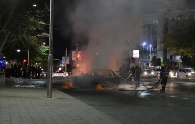 Firefighters extinguish a car that police said was set on fire during a confrontation between Uber and metered taxi drivers in the Sandton financial district in Johannesburg, South Africa September 7, 2017.