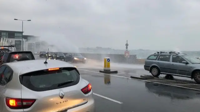 Waves crash over cars