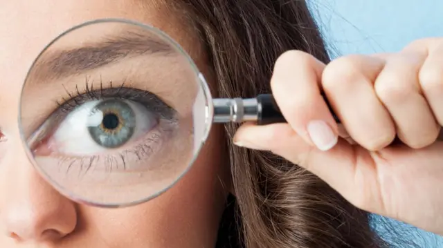 A woman looking through a magnifying glass