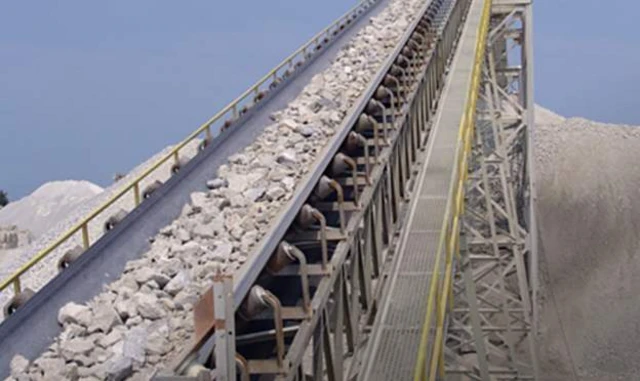 A conveyor belt  at a mine with rocks on it.