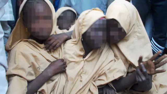 Three girls hold onto each other after being returned to Dapchi