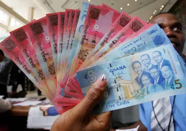 A woman holds a wad new currency, the new cedi, in Ghana in 2007