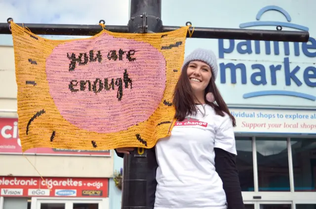 Stcie Clark with her pink and yellow 'yarn bomb'