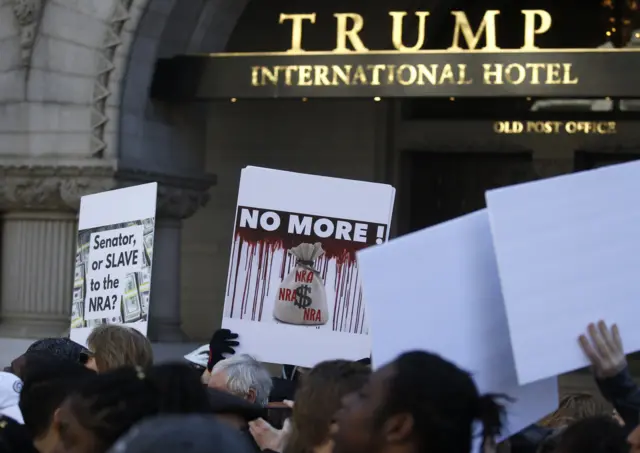 Participants hold up signs in front of the Trump International Hotel in Washington DC