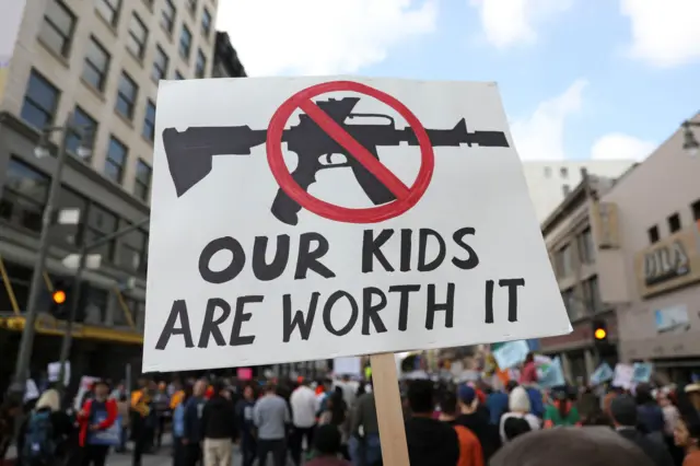 People walk with signs against assault rifles during "March for Our Lives", an organized demonstration to end gun violence, in downtown Los Angeles, California