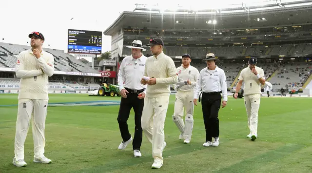 Players walk off as rain falls