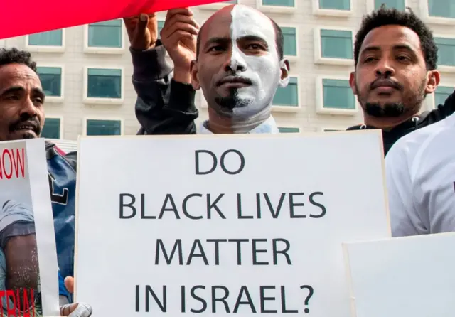 African migrants demonstrate with white paint on their faces, outside the Embassy of Rwanda in the Israeli city of Herzliya on February 7, 2018,