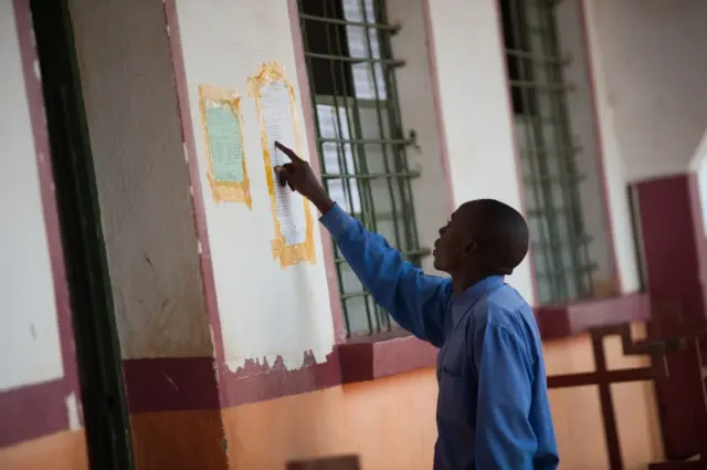 A man reads provisional election results showing a majority for incumbent president Kabila, posted at a polling station in the border town of Kipushi near Zambia on November 29, 2011