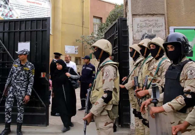 A woman leaves a polling station under heavy guard