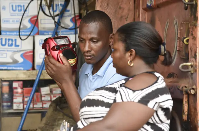 People listen to the radio as the results of the presidential elections are announced in Kireka, a Kampala suburb on February 20, 2016