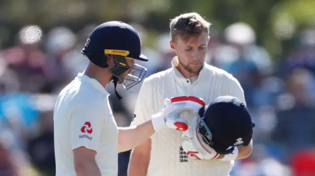 Joe Root examines his helmet