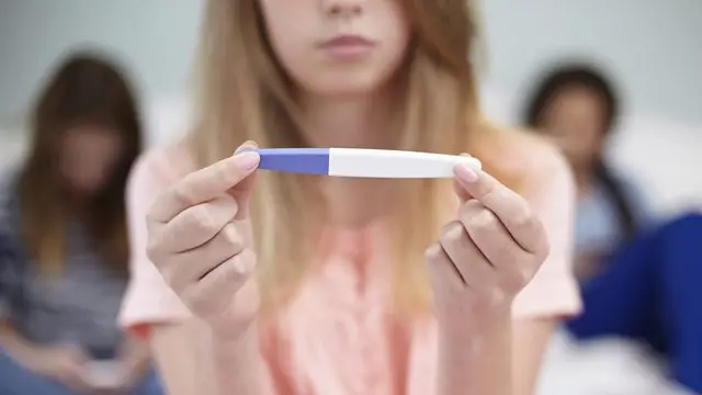 Young woman holds pregnancy test