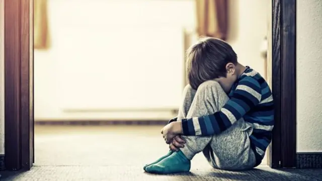 Child sitting with head between knees