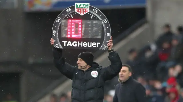The fourth official indicates ten minutes injury time