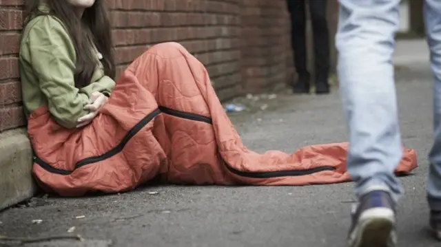 A young homeless girl sat on the street.