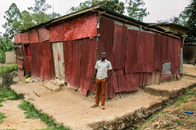 Pastor Eugene Nshyimiyabo stands near his made church 'The Holy City Church' made of iron sheets