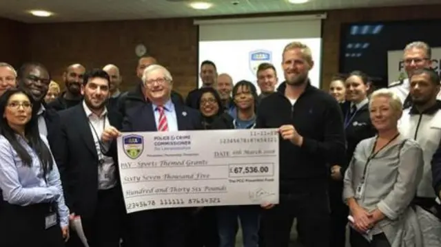 Leicester city goalkeeper holding cheque