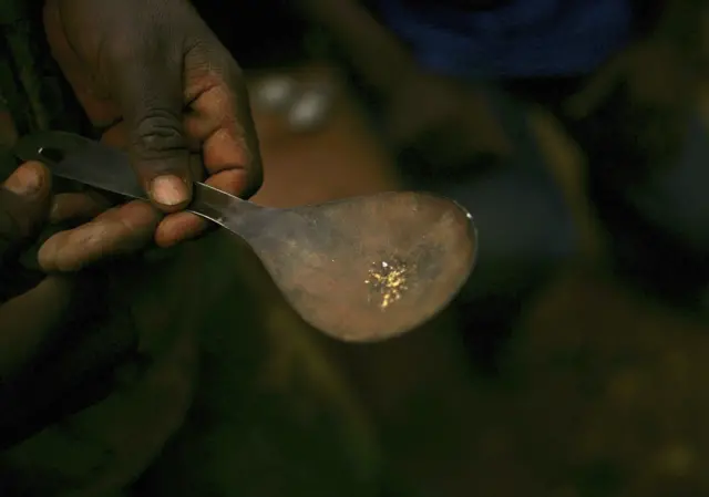 A man displays flakes of gold on a spoon March 27, 2006 in Mongbwalu, Congo.