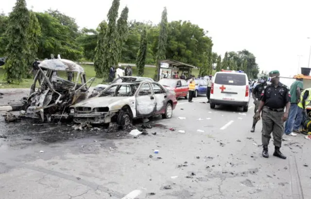 A picture taken on October 1, 2010 shows a policeman standing near a damaged car following a blast in Abuja during ceremonies for the 50th anniversary of the country's independence in Abuja.