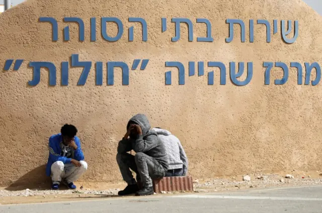 African migrants sit next to Holot open detention centre before marching in protest towards the Saharonim Prison where at least nine African migrants have been incarcerated as part of Israel"s new policy of prison or deportation for migrants, in Israel's southern Negev desert near the Egyptian border on February 22, 2018