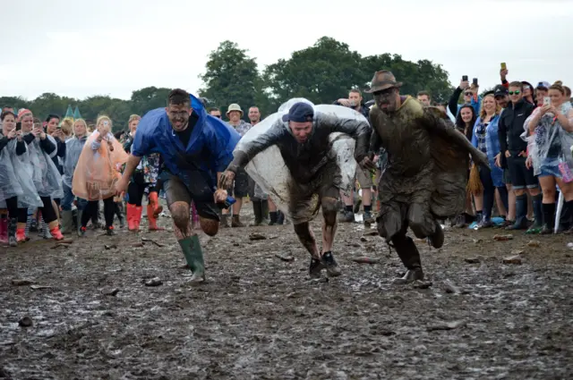 Festival-goers about to jump in the mud