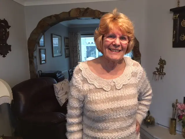 Joyce standing smiling in her living room