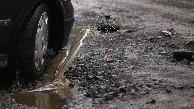 Car going through a water filled pothole