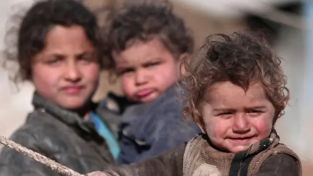 Syrian children stand near their tent in Ras al-Ain province, Syria