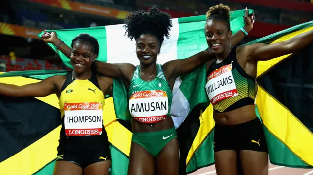 Oluwatobiloba Amusan of Nigeria celebrates winning gold with silver rmedalist Danielle Williams of Jamaica and bronze medalist Yanique Thompson of Jamaica