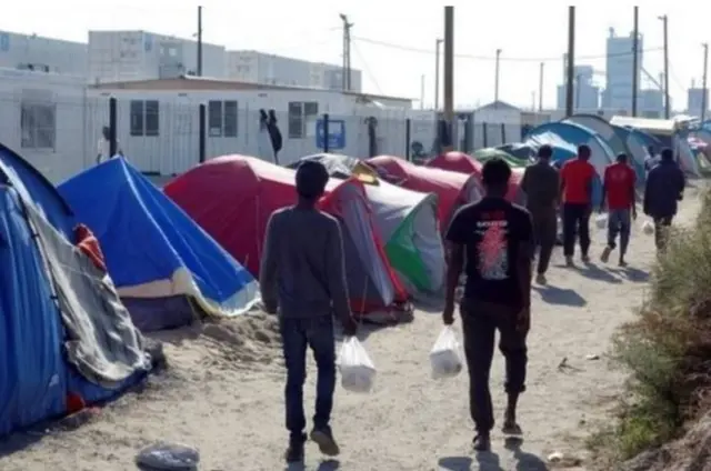 People walking past tents in Calais